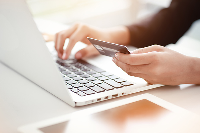 Hand typing on laptop and credit card in the other hand