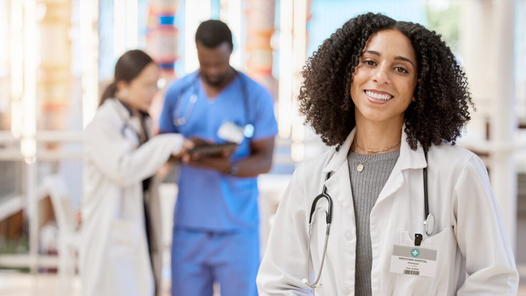 A woman in a lab coat is standing in front of a group of people.