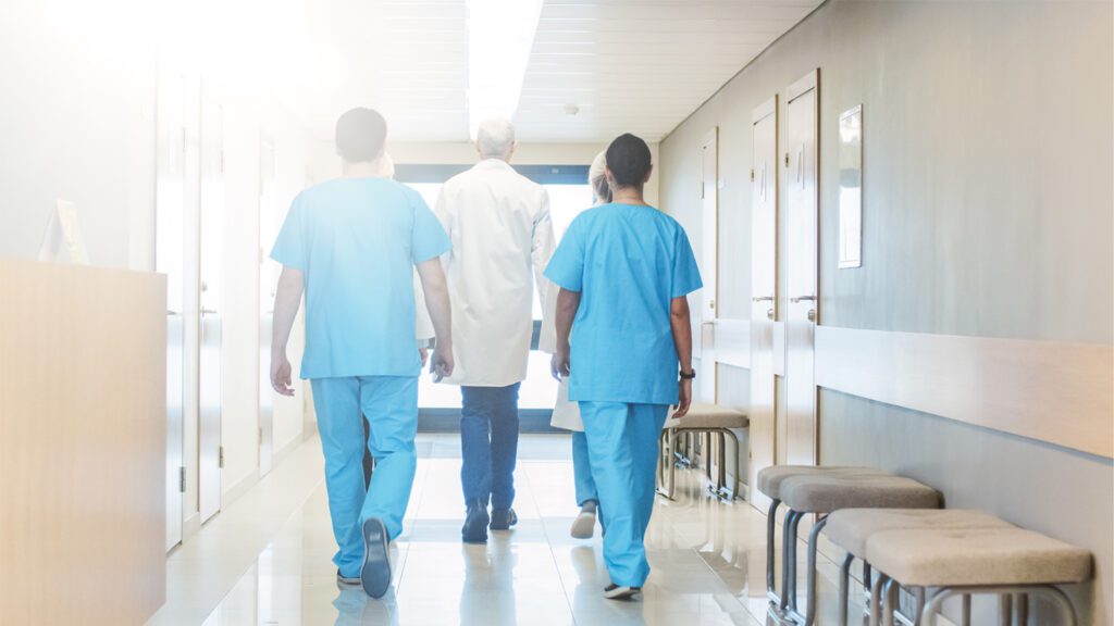 Three doctors walking down a hallway in a hospital