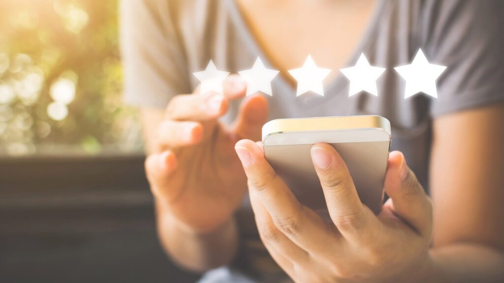 Person using a smartphone with a five-star rating graphic above.